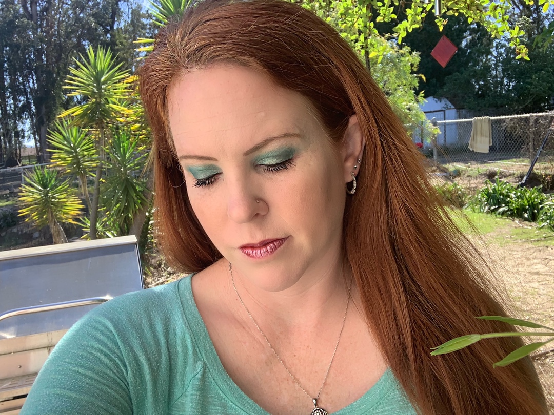 a woman with green eyeshadow posing for a selfie