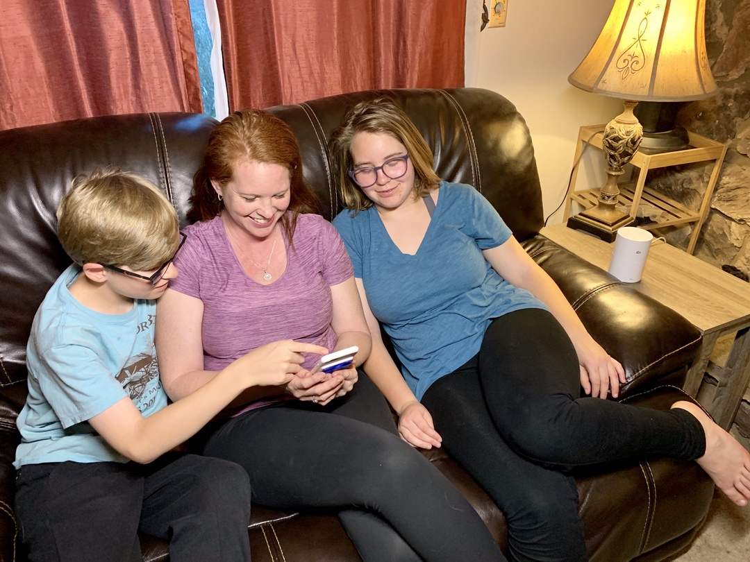 family looking at pictures on phone sitting on couch with photo storage hardware