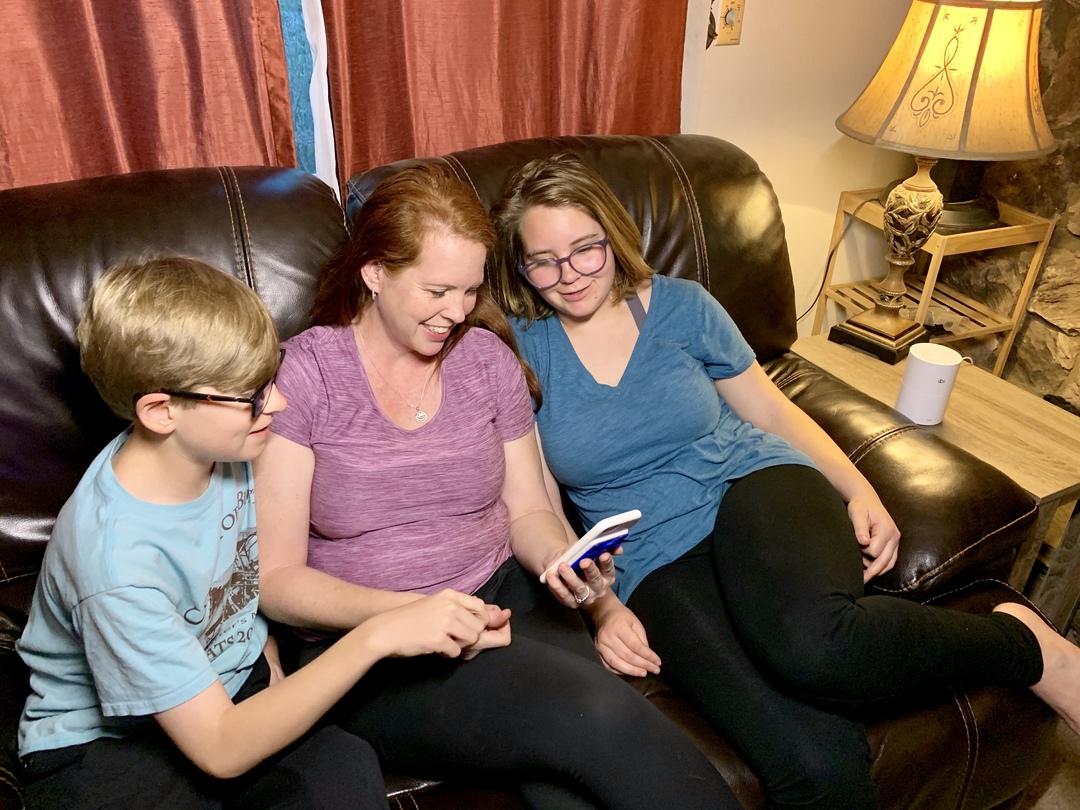 family looking at pictures on phone sitting on couch