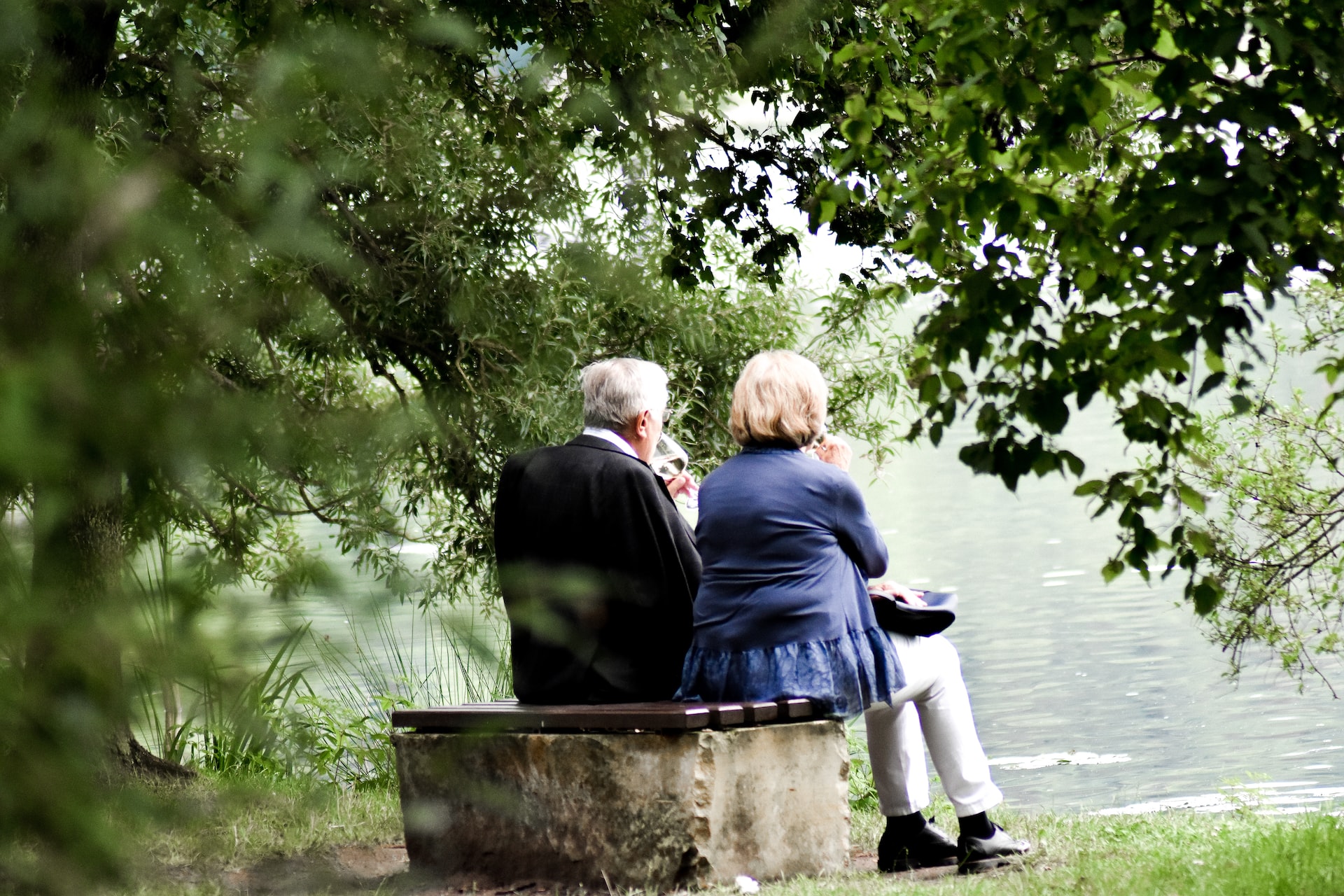 elderly people on bench by lake